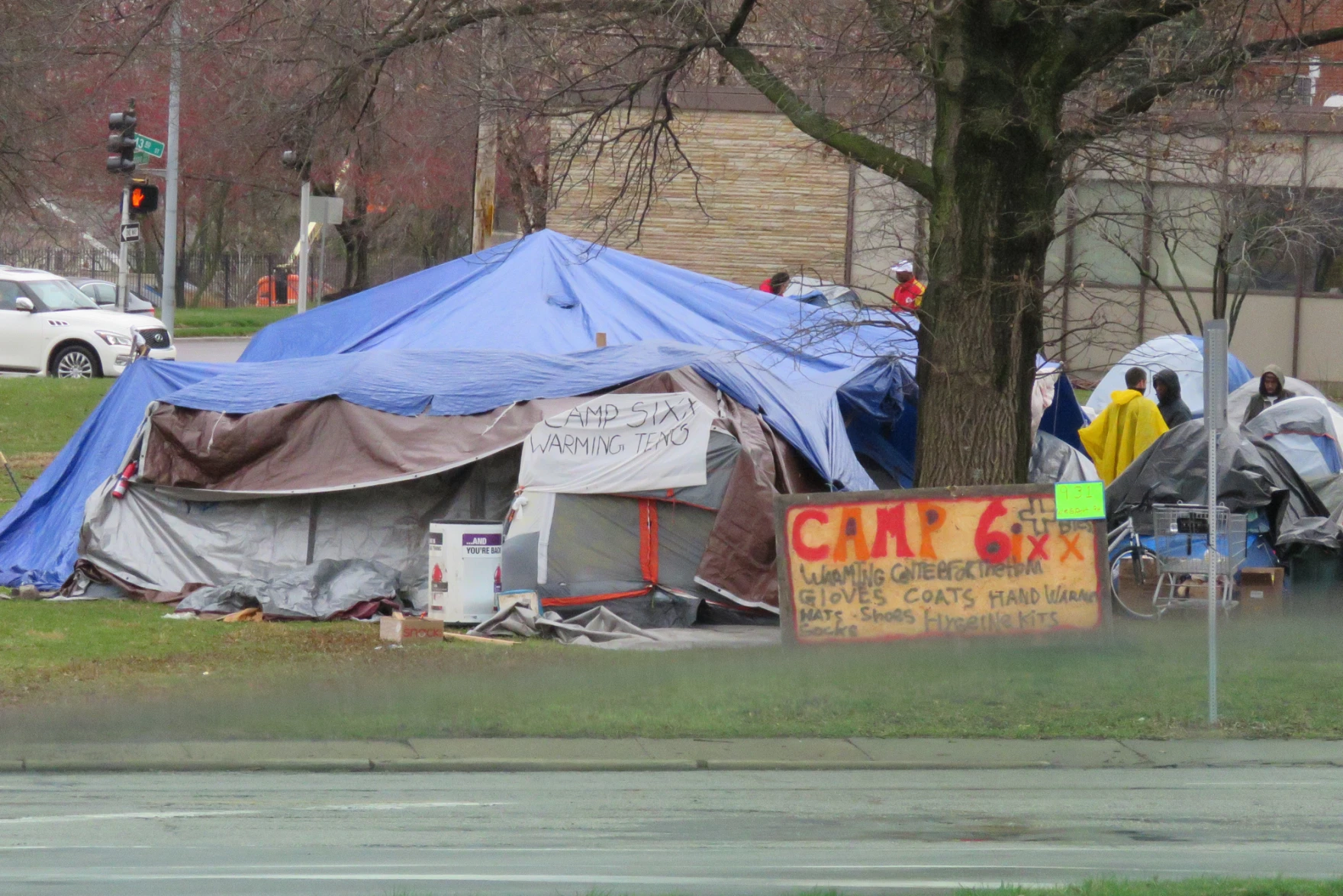 A large encampment covered by blue tarps near a city street